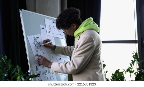 Side View Of African American Designer Drawing Sketches On Flip Chart In Studio 