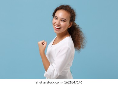 Side view of african american doctor woman isolated on blue wall background. Female doctor in medical gown clenching fist like winner. Healthcare personnel health medicine concept. Mock up copy space