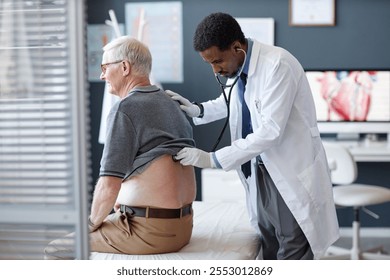 Side view of African American doctor using stethoscope and listening to heart and breathing while examining senior patient during checkup in clinic, copy space - Powered by Shutterstock