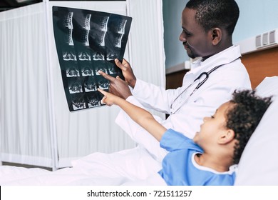 Side View Of African American Doctor And Little Patient Looking At Xray Picture Together In Hospital