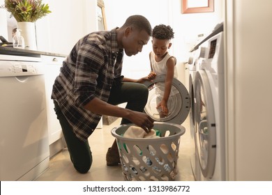 Side view of African American father and son washing clothes in washing machine at home. Social distancing and self isolation in quarantine lockdown for Coronavirus Covid19 - Powered by Shutterstock