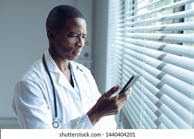 Side View Of African American Male Doctor Using Mobile Phone In Hospital