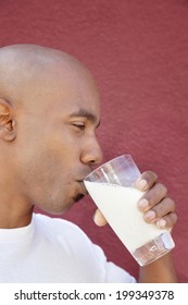 Side View Of An African American Man Drinking Milk Over Colored Background