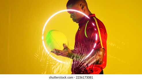 Side view of african american rugby player holding ball by circle and plants on yellow background. Illuminated, copy space, composite, sport, competition, shape, nature, playing, match and abstract. - Powered by Shutterstock