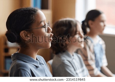 Side view of African American schoolgirl singing song together with other children in music class