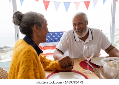 Side view of African American senior man holding hands of senior African American woman while having meal on a dining table at home - Powered by Shutterstock