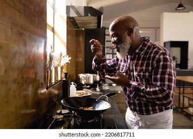 Side view of an African American Senior man at a cookery class, tasting hot vegetables. Active Seniors enjoying their retirement. - Powered by Shutterstock