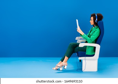side view of african american using digital tablet and listening to music on blue background