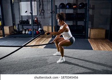 Side view of an African American woman with dark curly hair exercising at the gym