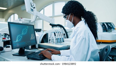 Side view of African American young female medical expert sitting at workplace in lab working typing on computer looking at molecular structure. Scientist using computer in his modern laboratory - Powered by Shutterstock