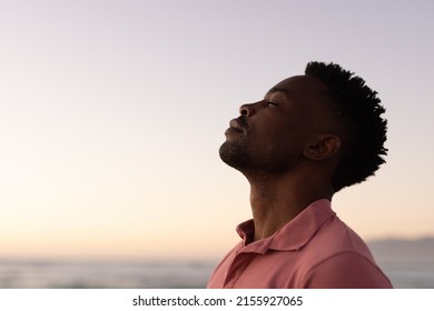 Side view of african american young man with eyes closed at beach against clear sky during sunset. copy space, nature, unaltered, beach, lifestyle, enjoyment and holiday concept. - Shutterstock ID 2155927065