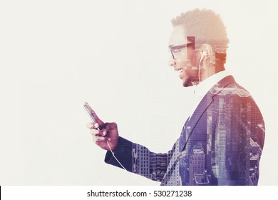 Side view of an African businessman listening to the music on his smartphone and smiling. Mock up. Toned image. Double exposure - Powered by Shutterstock