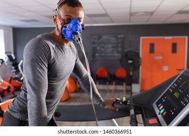 Side view of an African-American athletic man doing a fitness test using a mask while using a treadmill inside a room at a sports center. Athlete testing themselves with cardiovascular fitness test on - Powered by Shutterstock