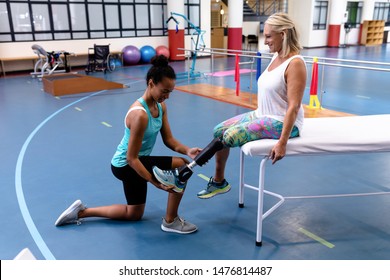 Side view of African-american female trainer adjusting prosthetic leg of disabled Caucasian active senior woman in sports center. Sports Rehab Centre with physiotherapists and patients working - Powered by Shutterstock