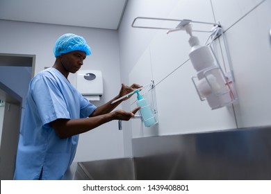 Side view of African-american male surgeon washing hands with soap in sink at hospital, Coronavirus hand washing for clean hands hygiene Covid19 spread prevention.