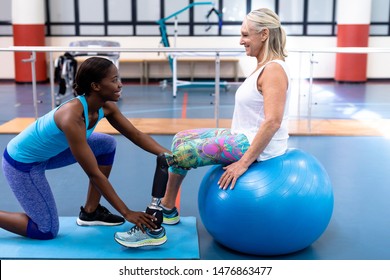 Side view of African-american  trainer assisting disabled Caucasian senior woman in sports center. Sports Rehab Centre with physiotherapists and patients working together towards healing - Powered by Shutterstock