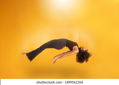 Side View Of Afro Hair Woman In Zero Gravity Or Being Abducted By A UFO. Girl Is Flying Or Floating In The Air. Side View Of Person. Over Yellow Background. Spiritism. Rising To The Heaven.