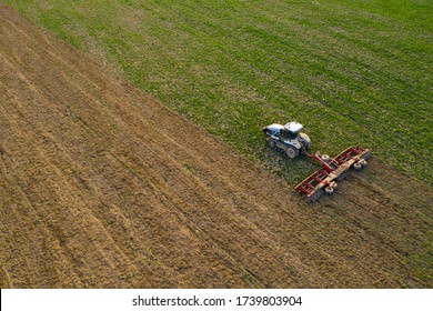 Side view of an aircraft flying over a field cultivated by a crawler tractor during a crisis in the agro-industrial sector