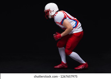 Side view of American football player wearing helmet taking position while playing against black background - Powered by Shutterstock