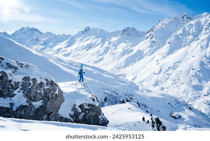 Side view of anonymous sportsman in warm sportswear and hat standing on snowy mountain while pointing away with ski and admiring snowy landscape - Powered by Shutterstock