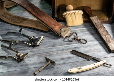 Side View Of Antique And Vintage Tools For Barbers, Razor, Sharpen The Blade In
Leather Brush, Clipper And Razor Blades On A Rough Black Wooden Background