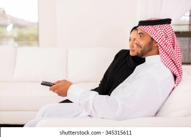 Side View Of Arabian Couple Watching Tv In The Living Room At Home