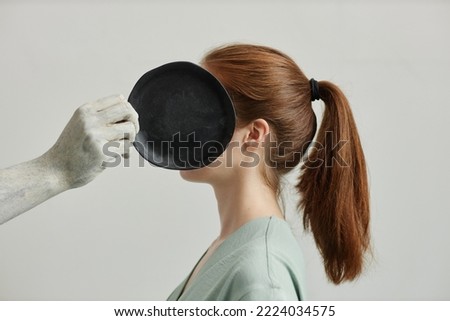 Side view of artist covering face of young woman with black handmade ceramics