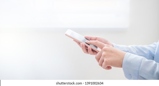 Side View Of Asia Young Business Woman In Blue Shirt Dress Standing Beside Window And Using Smart Phone In Bright Office Room, Copy Space, Close Up