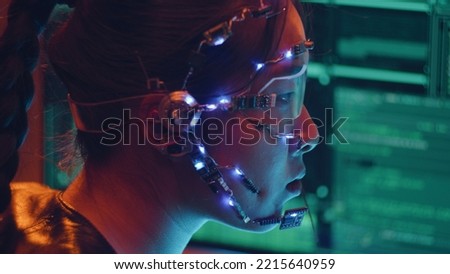 Side view of an Asian girl with futuristic headset and microphone programming using multiple computer screen. Cyperpunk style. Sci-fi background.