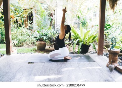 Side View Of Asian Girl Practicing Yoga On Wooden Terrace. Harmony And Mental Health. Young Beautiful Woman With Closed Eyes Wearing Sportswear And Barefoot On Fitness Mat. Bali Island. Sunny Day