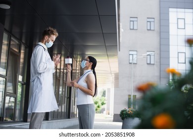 Side View Of Asian Journalist With Microphone Taking Interview Of Doctor Near Clinic