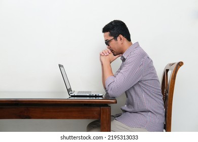 Side View Of Asian Man Looking To His Laptop With Serious Focus Expression