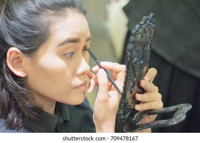 Side View Of Asian Woman Applying Make Up (paint Her Eyelashes) For Working Time.