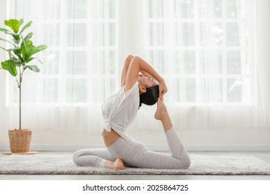 Side view of Asian woman doing Yoga exercise,Yoga One Legged King Pigeon pose or Eka Pada Rajakapotasana,Calm of healthy young woman breathing and meditation with yoga at home - Powered by Shutterstock