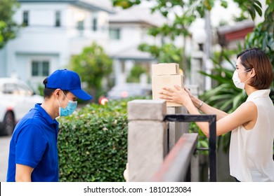 Side View Asian Woman With Face Mask Customer Take Shopping Packages From The Fence Post That Delivery Man Put Them On For Contactless Delivery. This Can Reduce Coronavirus COVID-19 Spreading.