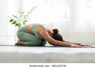 Side view of Asian woman wearing green sportwear doing Yoga exercise,Yoga Child’s pose or Balasana,Calm of healthy young woman breathing and meditation with yoga at home,Exercise for wellness life - Shutterstock ID 2011231742