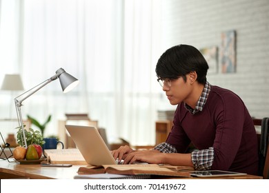 Side View Of Asian Young Man Concentrated On Work