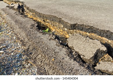 Side view asphalt road broken due to collapsing ground until the grass grows 