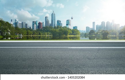 Side view of asphalt road highway with lake garden and modern city skyline in background. - Shutterstock ID 1405202084