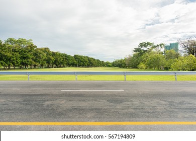 Side View Of Asphalt Road With Park In City