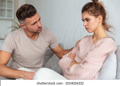 Side View Of Attentive Man Sitting On Couch And Calm Down His Offended Girlfriend At Home