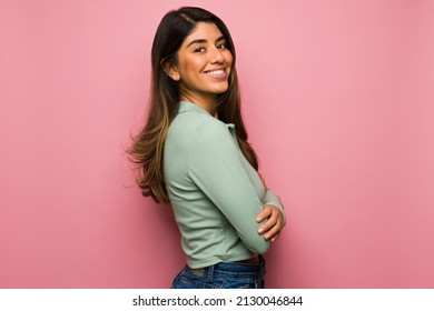 Side view of an attractive hispanic woman feeling happy in front of a bright pink background