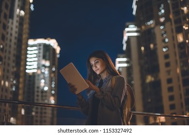 Side View Of Attractive Woman Using Digital Tablet On City Street At Night
