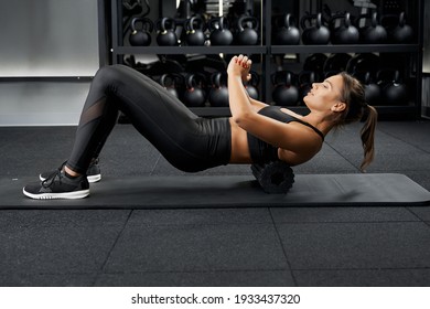 Side View Of Attractive Young Woman In Black Sportswear Doing Abs Exercise On Black Mat. Concept Of Workout In Modern Gym And Improving Body And Health.