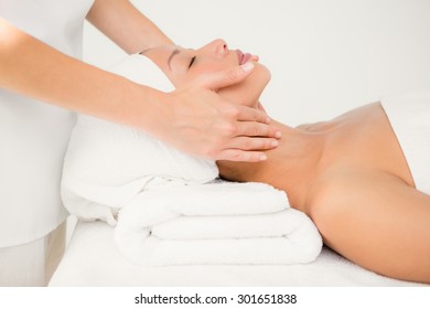Side view of an attractive young woman receiving facial massage at spa center
