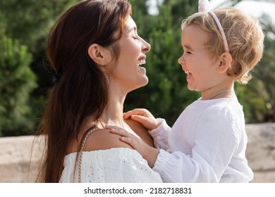 Side View Of Baby Daughter Laughing With Mother Outdoors In Valencia