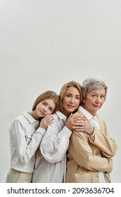 Side View Of Back To Back Of Caucasian Family Of Three Female Generations Look At Camera. Age And Generation Concept. Senior And Adult Women With Teenage Girl. Isolated Of White Background. Copy Space