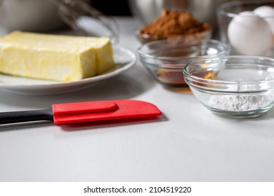 Side View Of Baking Ingredients.  Ingredients Include: Egg, Butter, Vanilla, Cocoa, And Baking Powder.