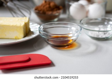 Side View Of Baking Ingredients.  Ingredients Include: Egg, Butter, Vanilla, Cocoa, And Baking Powder.