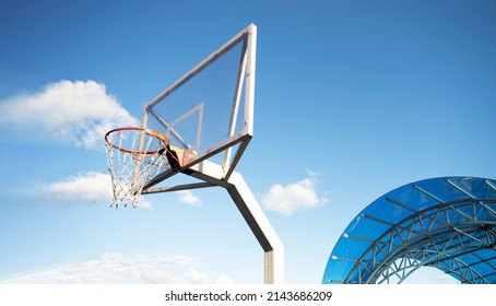 Side view of a basketball hoop with a backboard on a sports field, against a blue sky. Achievement, sports concept